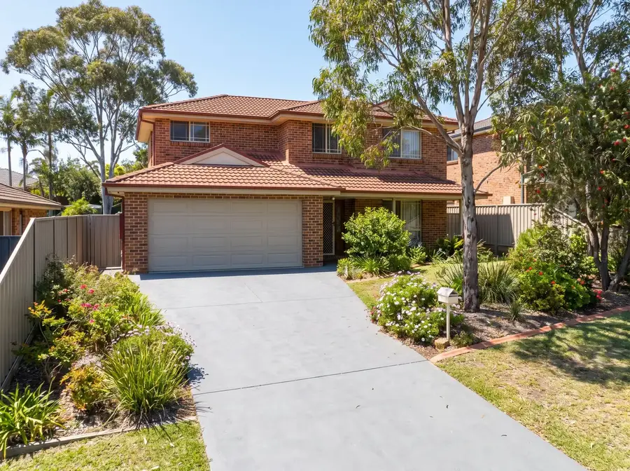 A plain grey concrete driveway running from a double garage down to the street edge of a suburban block