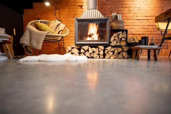 Cozy fireplace with firewood in the loft style home interior with brick wall background, burning fire in the fireplace, Image with copy space on the floor